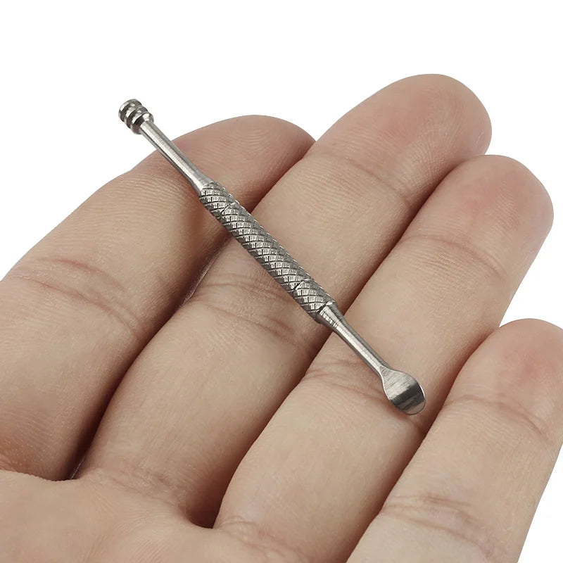 Silver ear cleaning tool held between fingers on a white background