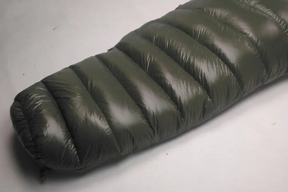 green sleeping bag on a gray background