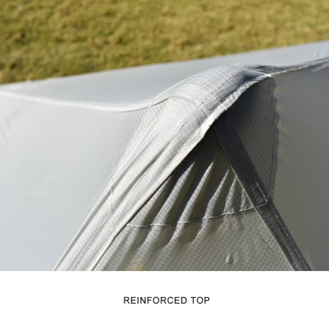 Close-up of a tent with a reinforced top section, grassy background.