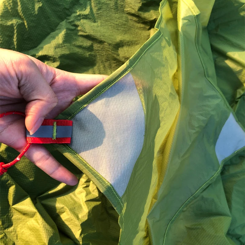 Close-up of a hand holding a red and blue tag inside a green fabric