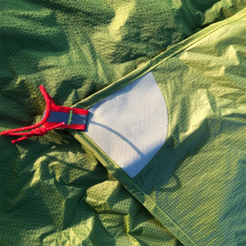 Green fabric with a white reinforcing patch and red drawstring on a green background
