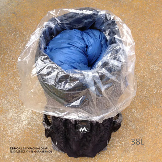 Black backpack with blue sleeping bag inside, covered by a clear plastic bag on a beige surface.