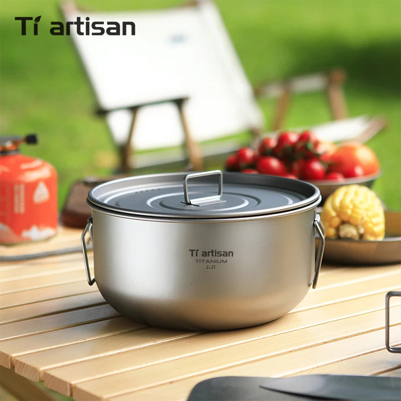 Titanium pot with lid on a wooden surface outdoors, featuring Tiartisan branding.