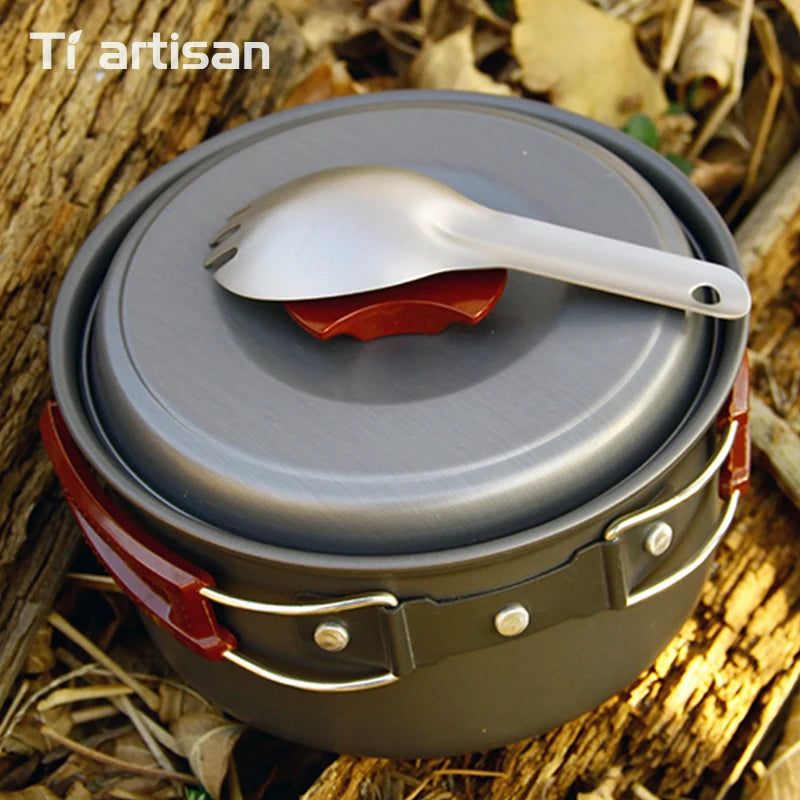 Camping cookware set with lid and spoon on a natural background
