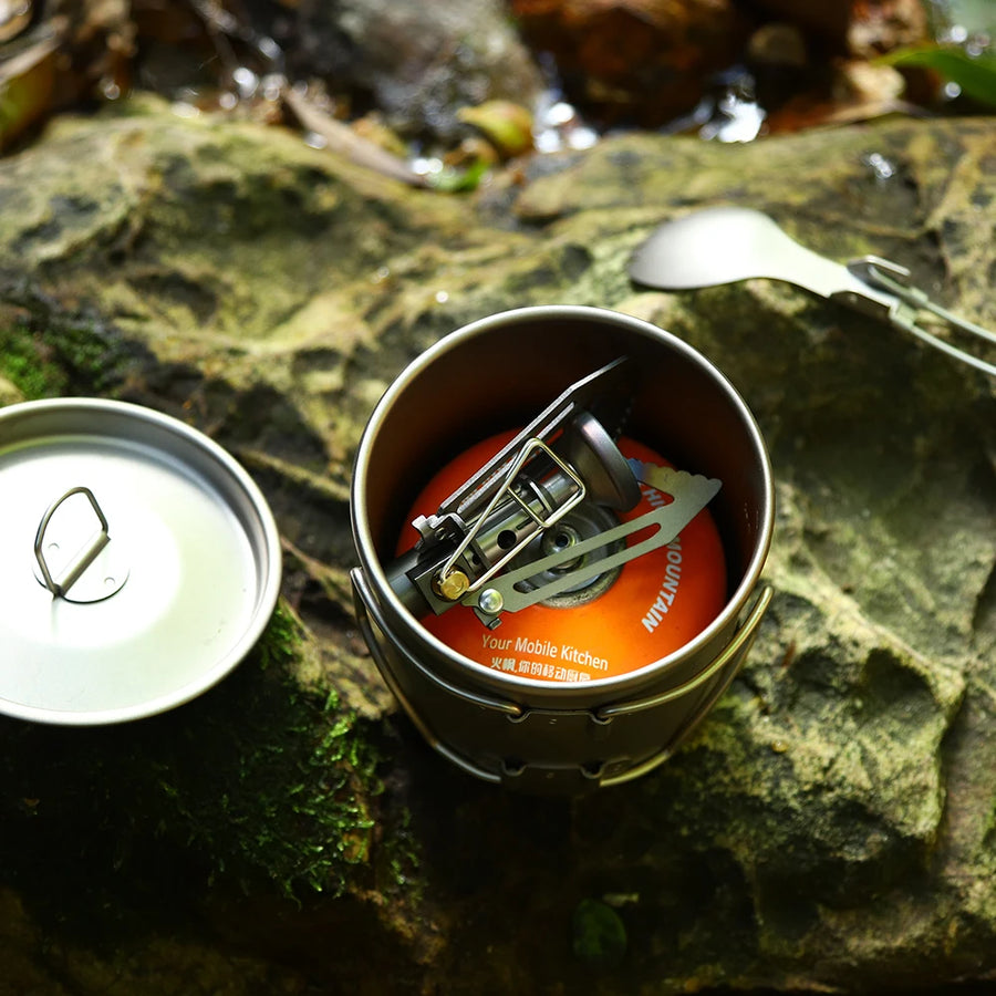 Portable camping stove on a rock with a spoon and fork nearby