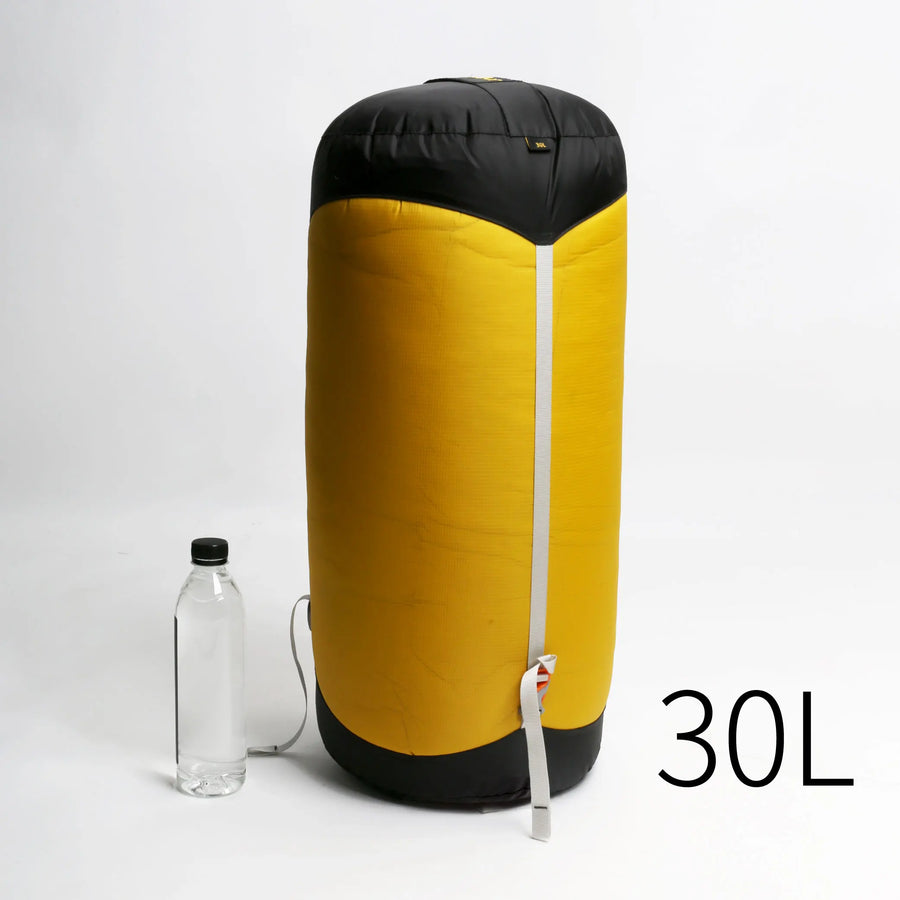 Yellow and black 30L compression sack with a water bottle on a white background