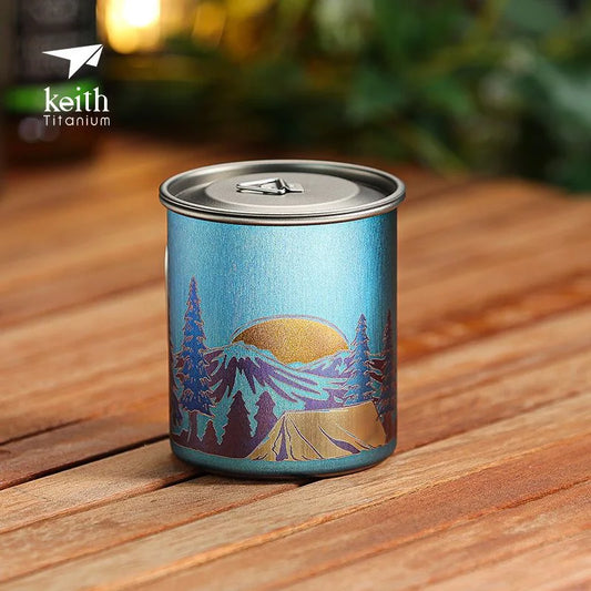 Blue mug with mountain design on a wooden surface, featuring the Keith Titanium logo.