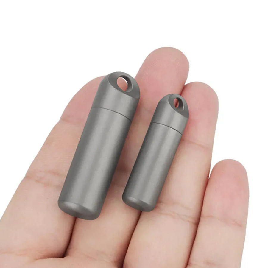 Two small metallic cylindrical objects held between fingers on a white background