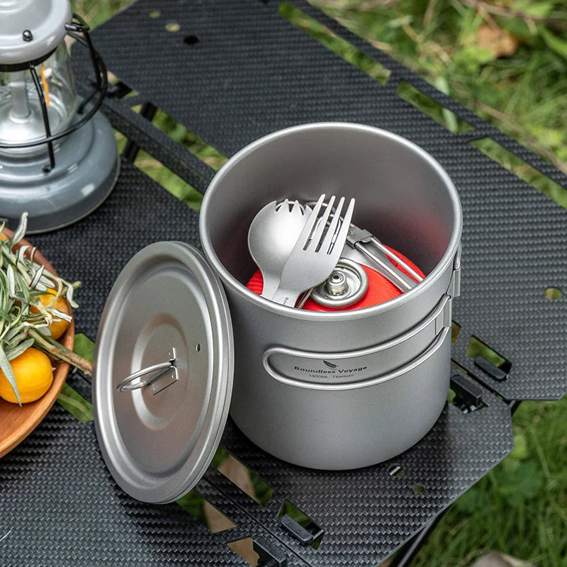 Camping cookware set with utensils on a camping mat outdoors