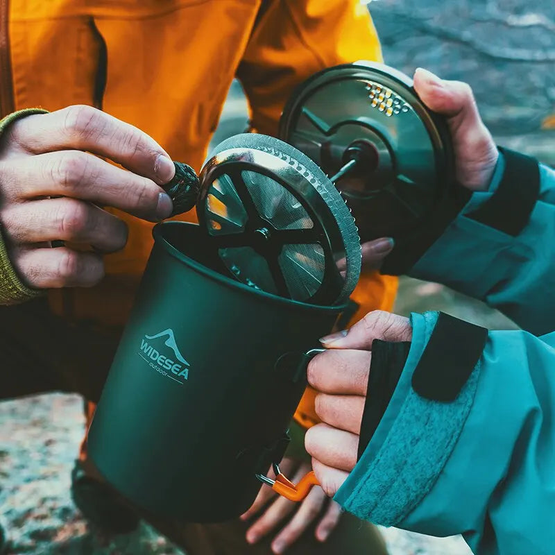 Person holding a green mug with a lid, outdoors