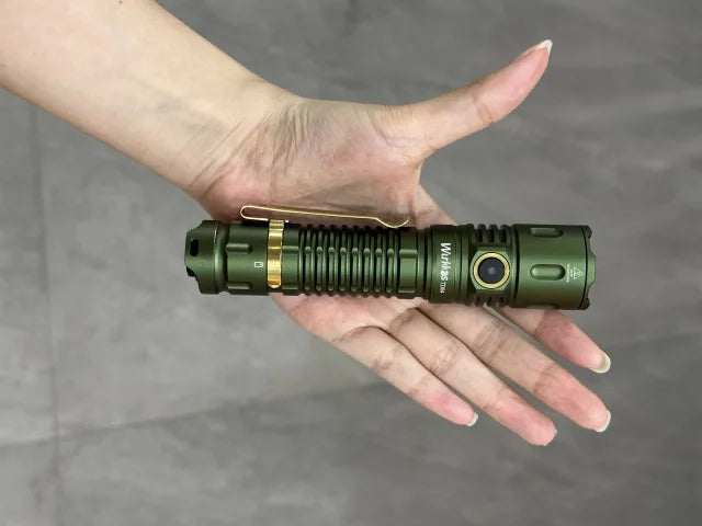 Green flashlight held in a hand against a gray background