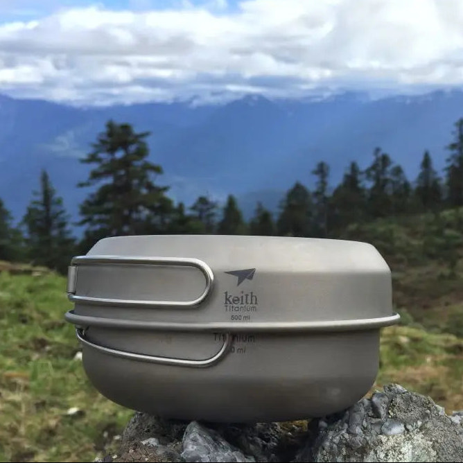 Camping pot with lid on a rock in front of a mountainous landscape