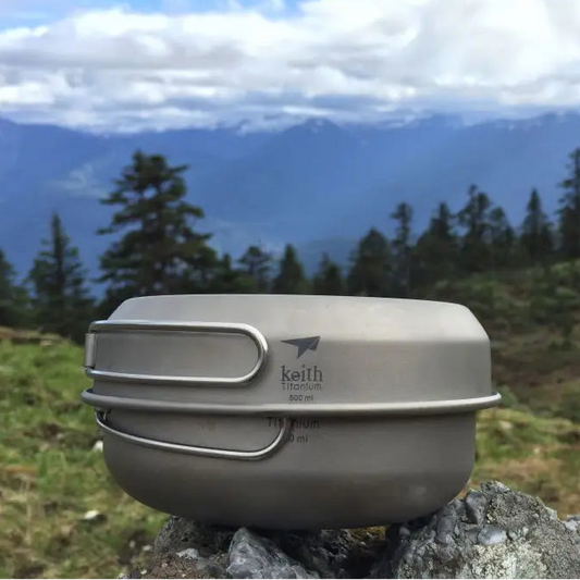 Camping pot with lid on a rock in front of a mountainous landscape