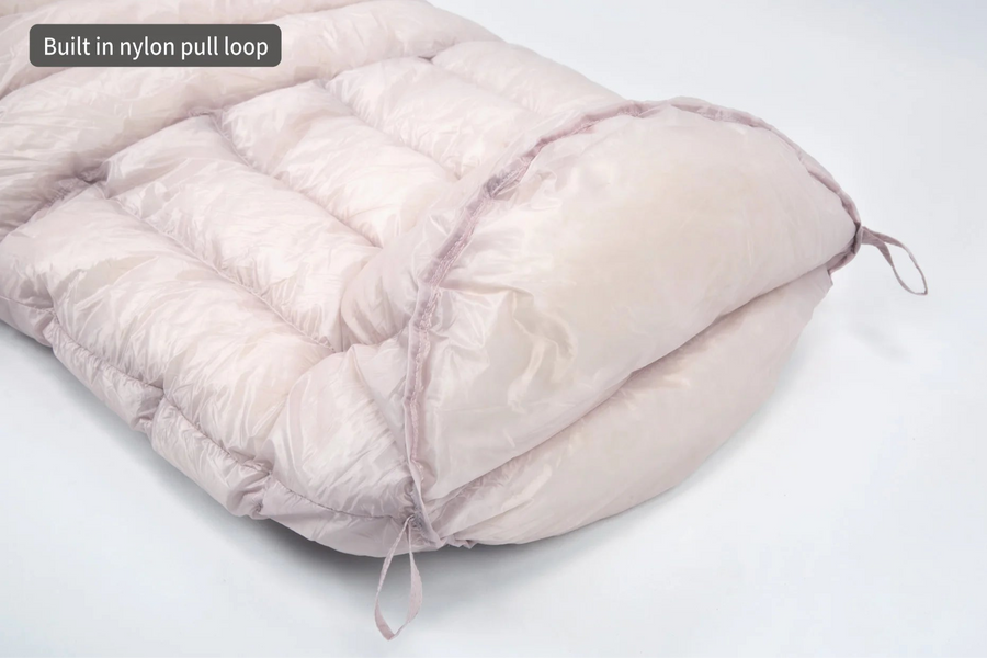 Pink sleeping bag with a built-in nylon pull loop on a white background