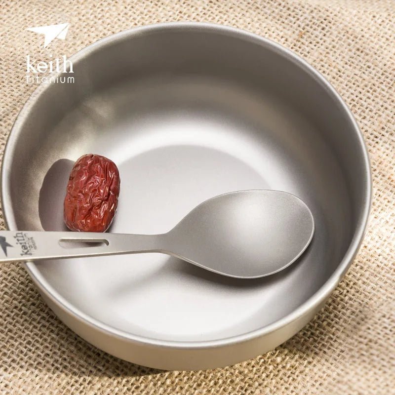 titanium bowl with spoon and date on a textured beige background, featuring the Keith Titanium logo.