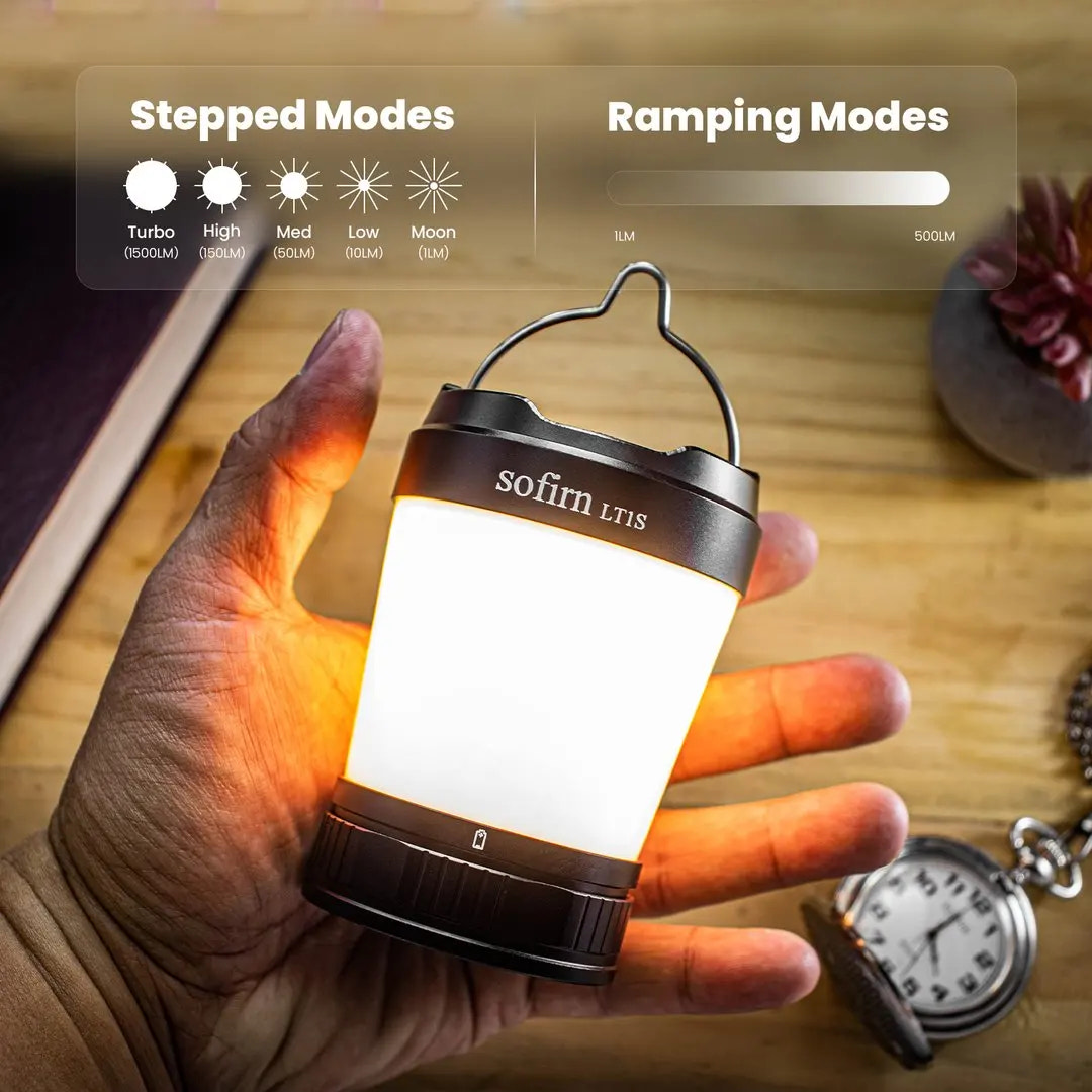 Hand holding a lantern with 'sofin LT1S' branding, showing light modes on a wooden surface.