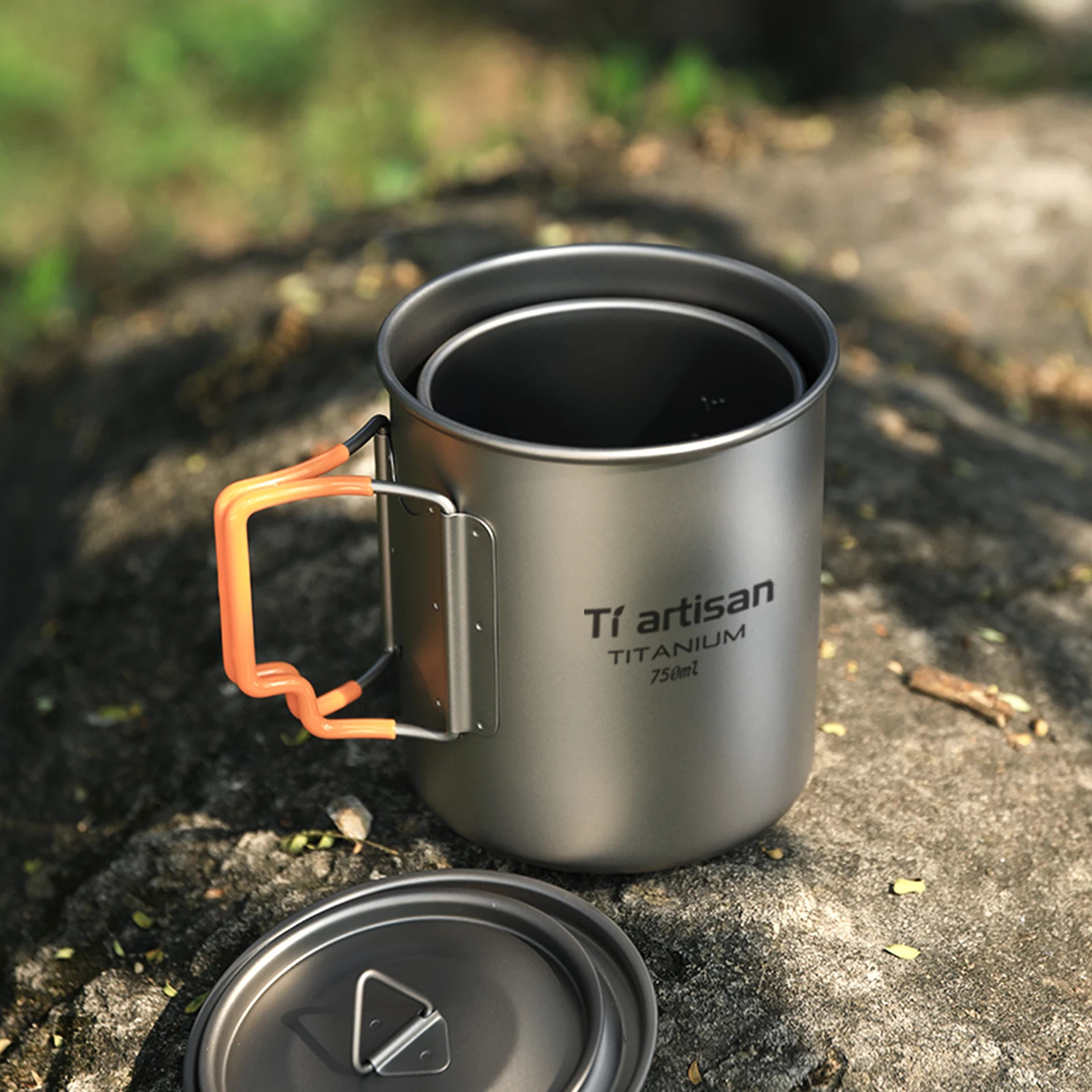 Titanium mug with orange handle on a natural background