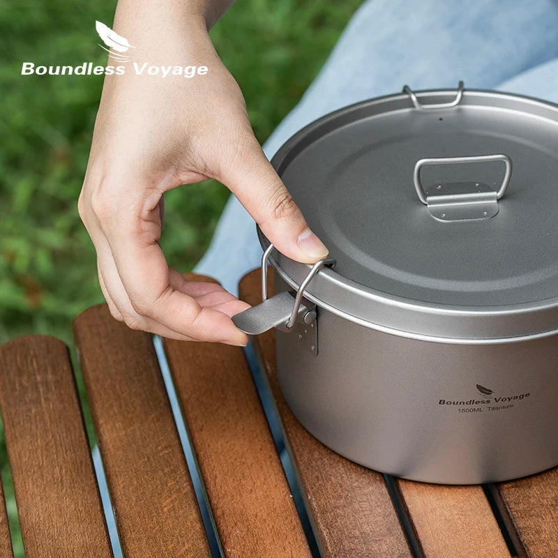 Hand opening a camping pot with 'Boundless Voyage' branding on a wooden surface.