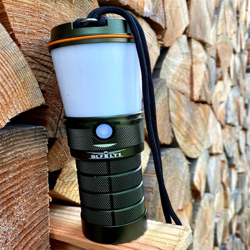 Green camping lantern on a stack of wooden logs