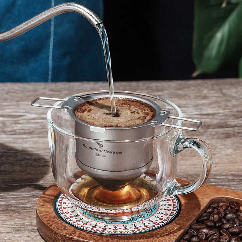 Coffee brewing process with a glass mug and metal filter on a wooden coaster.