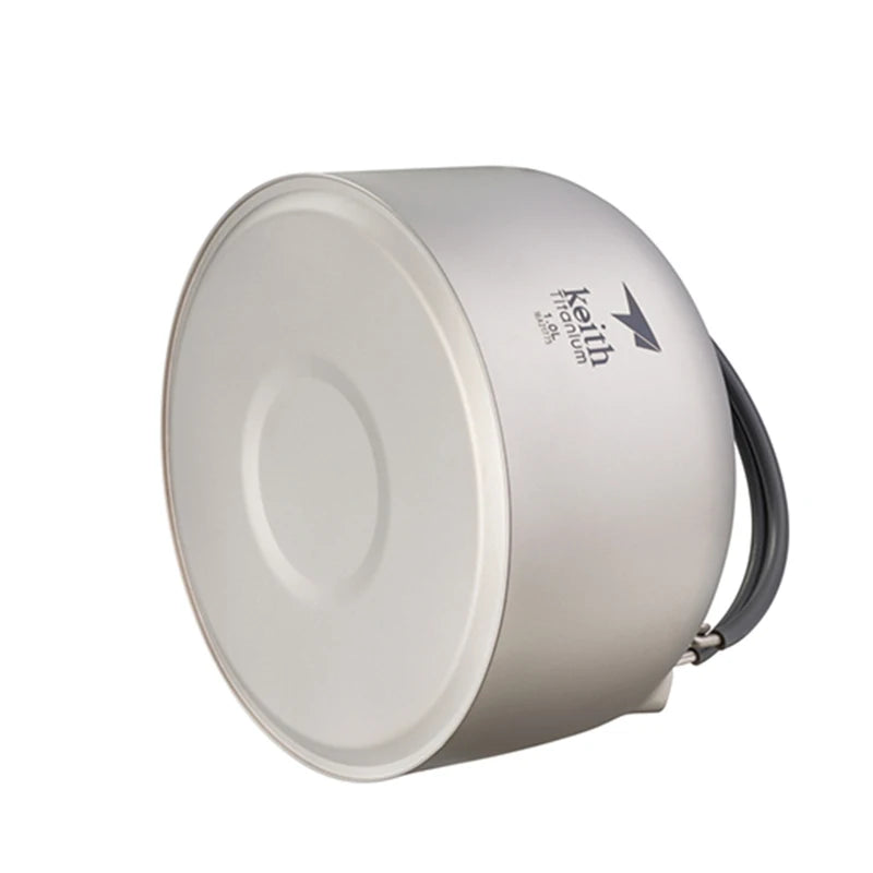 titanium camping pot with a handle on a white background