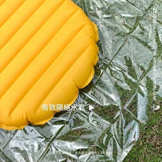 Yellow inflatable mattress on a plastic sheet with grass underneath