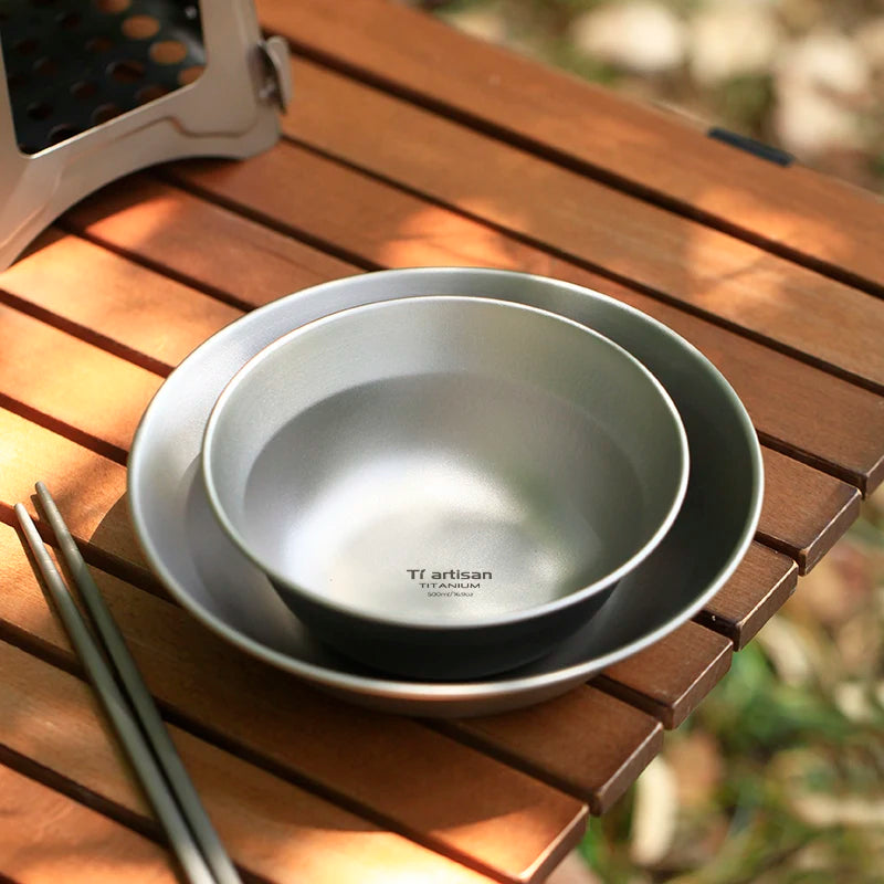 Two titanium bowls with a brand label on a wooden surface
