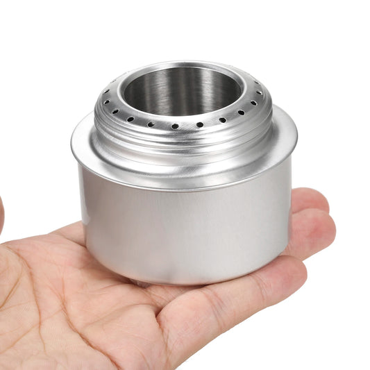 alcohol stove held in a hand against a white background