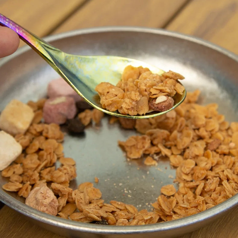 Spoonful of cereal over a metal bowl on a wooden surface
