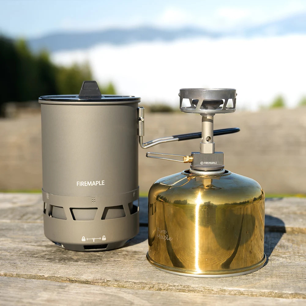 Portable camping stove with fuel canister on a wooden surface outdoors