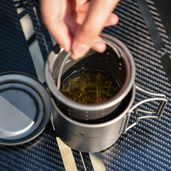 Silver camping mug with tea leaves on a textured surface