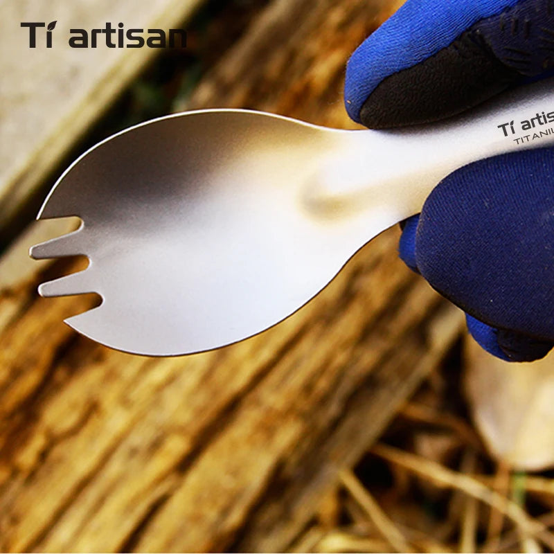titanium fork and spoon set held by a gloved hand against a wooden background, with 'Tiartisan' branding.