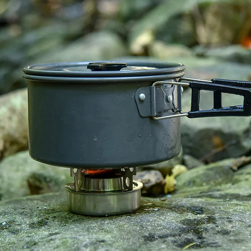 Portable camping stove with pot on a rocky surface