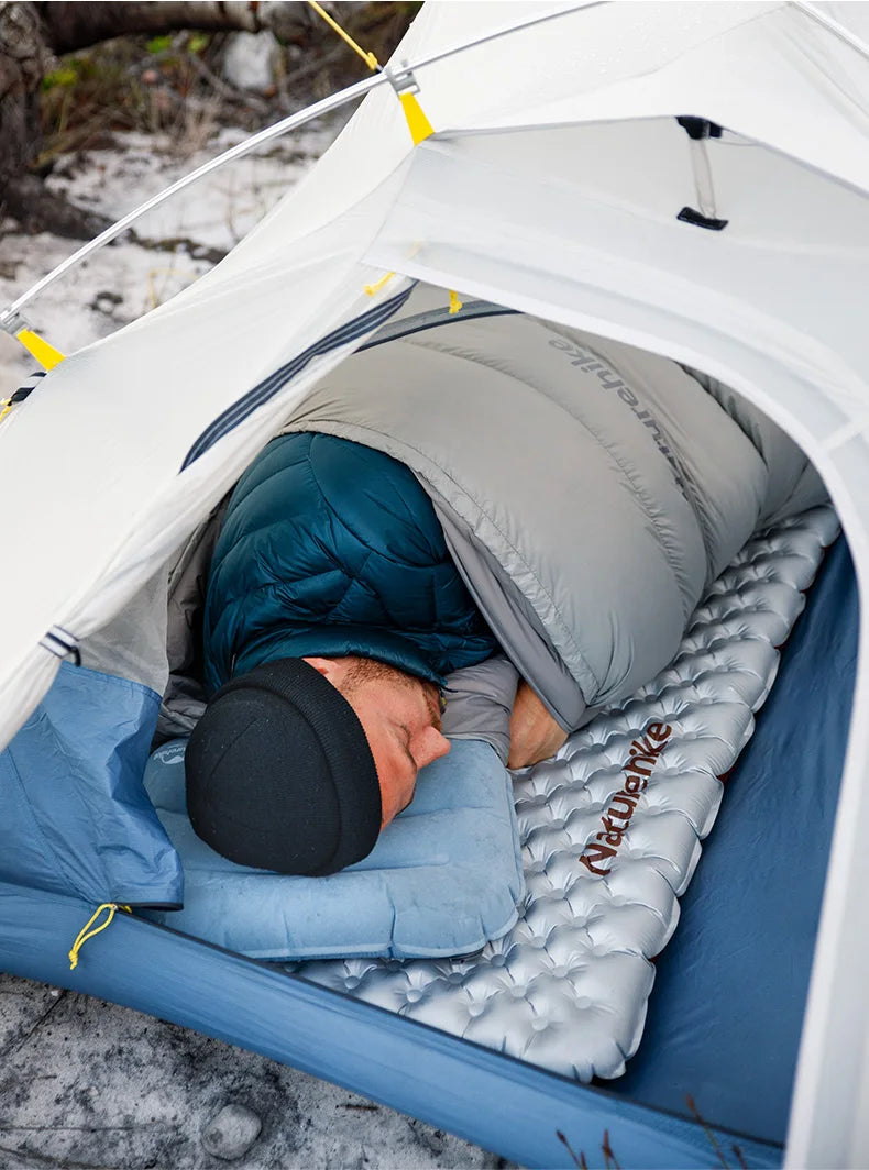 Person sleeping in a tent with a sleeping pad on a snowy ground