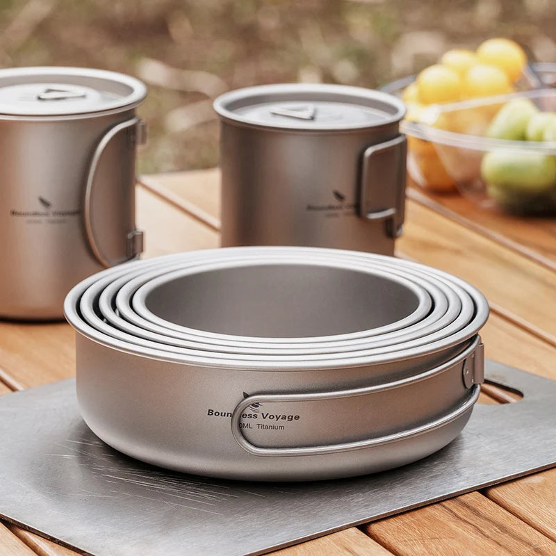 Stack of titanium cookware on a wooden table with a blurred background