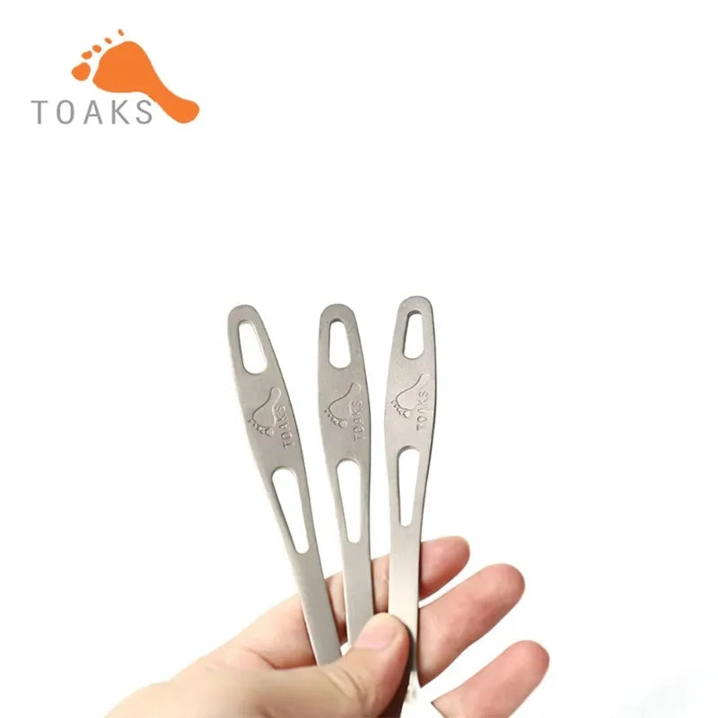 Three metal tools held by a hand with 'TOAKS' branding above.