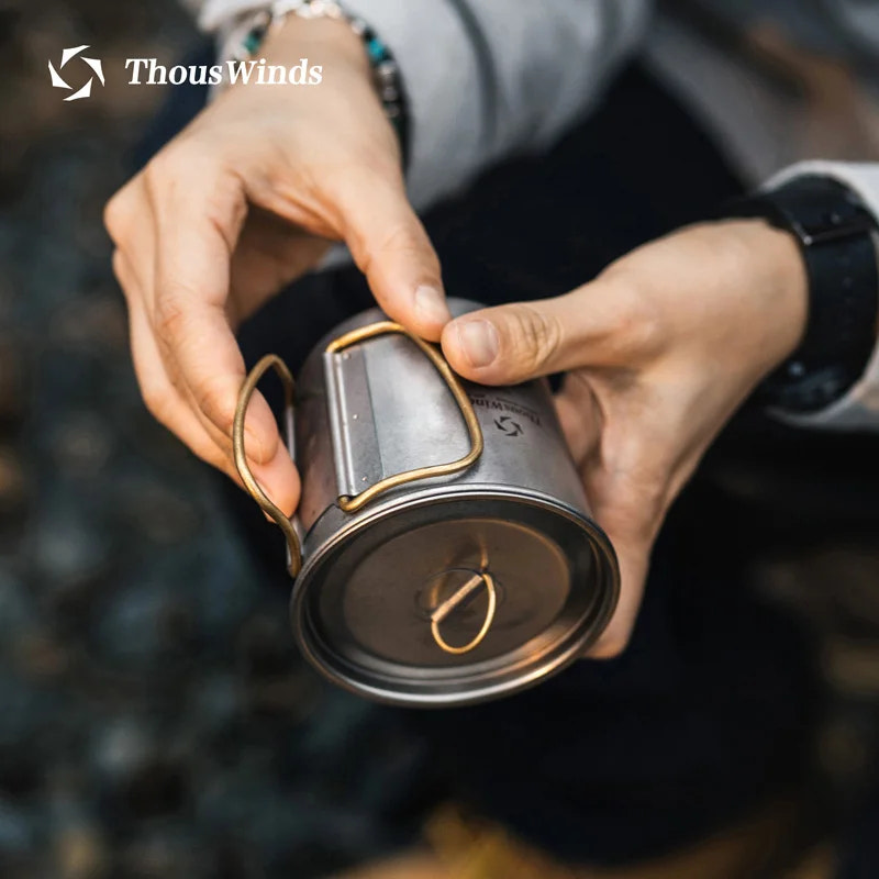 Person holding a metal mug with a blurred background