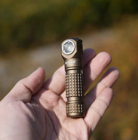 Brown flashlight held in a hand with a blurred natural background