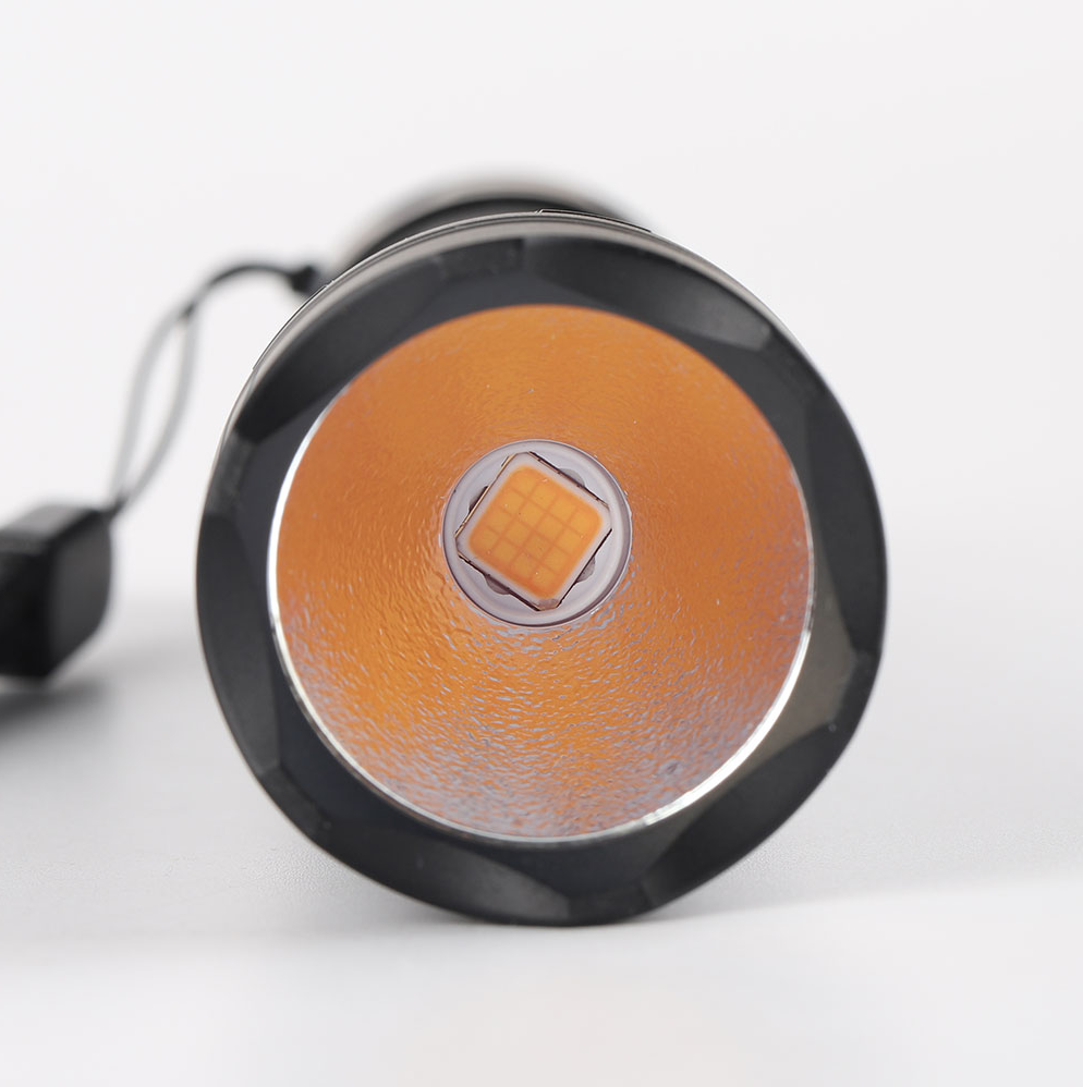 Close-up of a round flashlight with orange lens and black casing on a white background