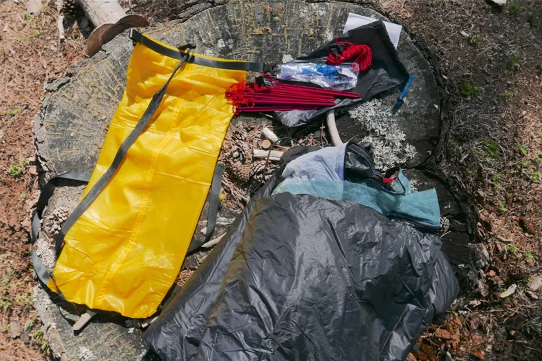 Yellow bag and tent components on a stone surface