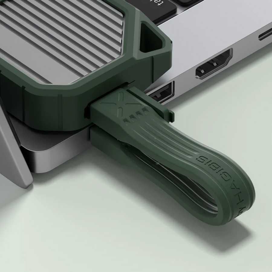 Green USB-C adapter attached to a laptop on a light gray background