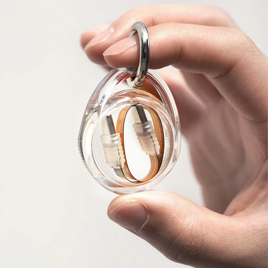 Clear container holding a usbc cable with a hand holding it against a light background