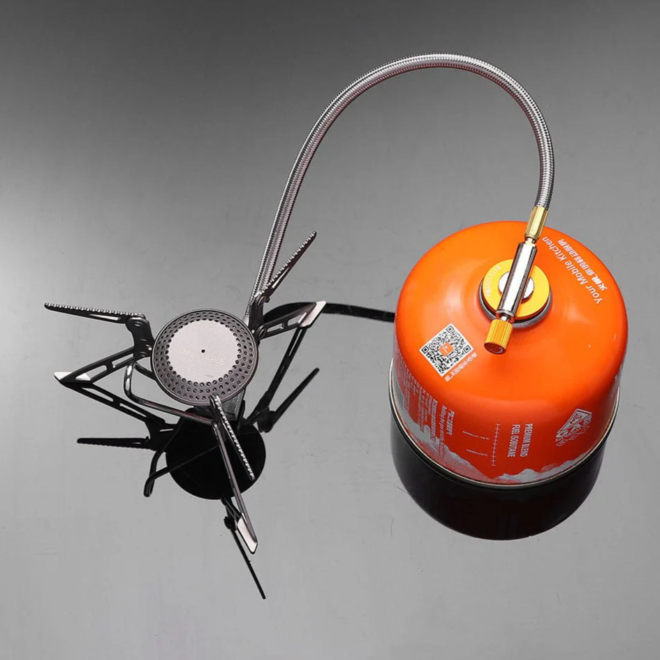Portable camping stove with orange fuel canister on a gray background