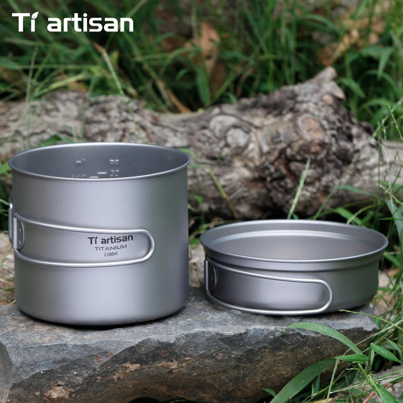 Two Tiartisan titanium cookware pots on a natural background with grass and logs.