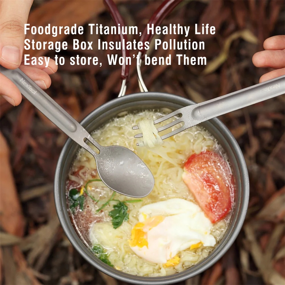 Metallic food container with spoon and fork, containing a meal with an egg and tomato, on a natural background.