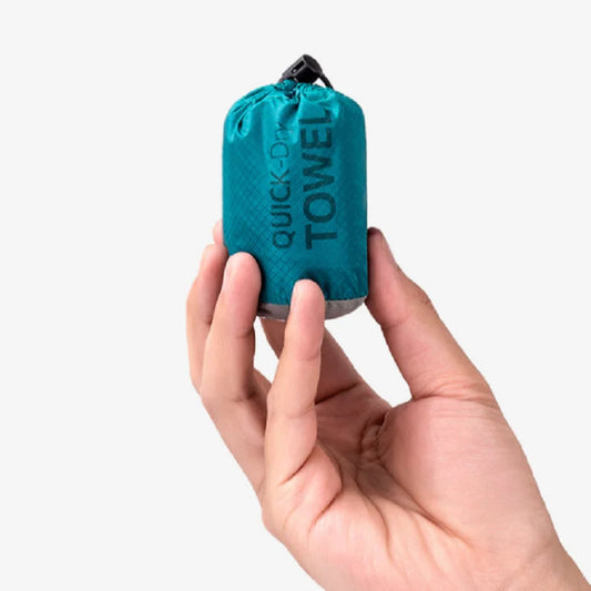 Teal quick-dry towel held in a hand against a white background