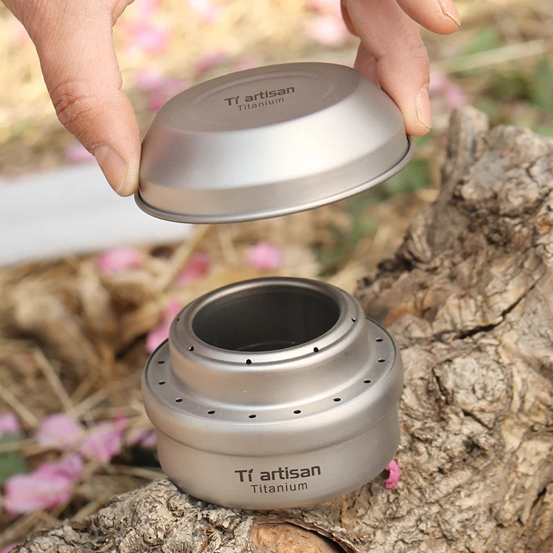 Titanium camping pot with lid held by a hand on a natural background