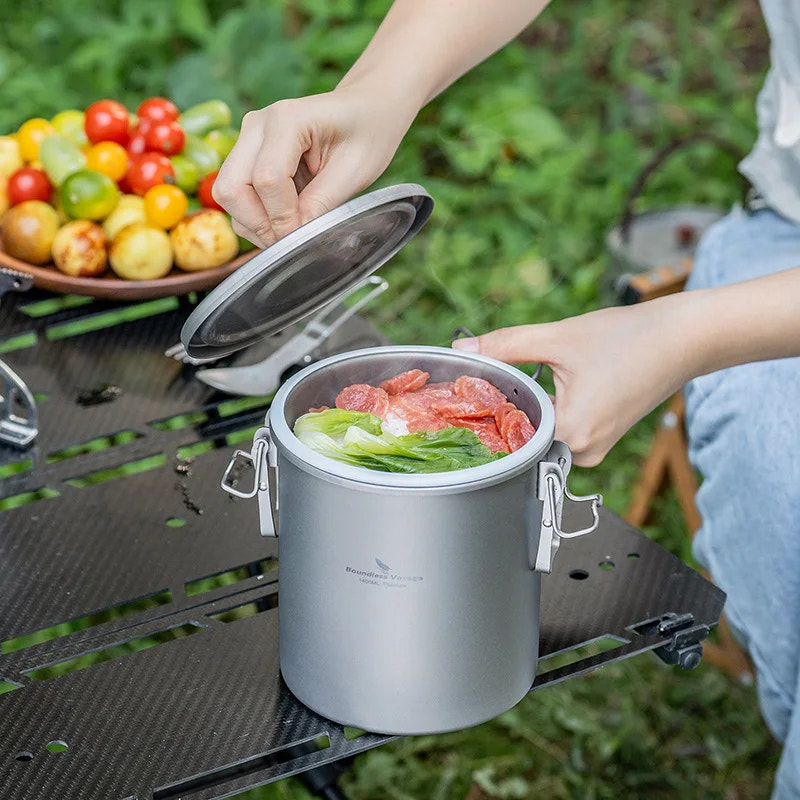 Person preparing food in a portable stove outdoors with vegetables on a table.