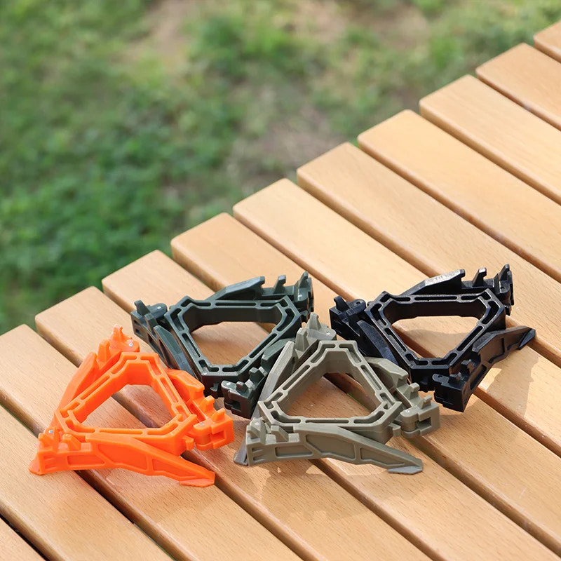 Three plastic clips in black, gray, and orange on a wooden surface with a blurred green background.