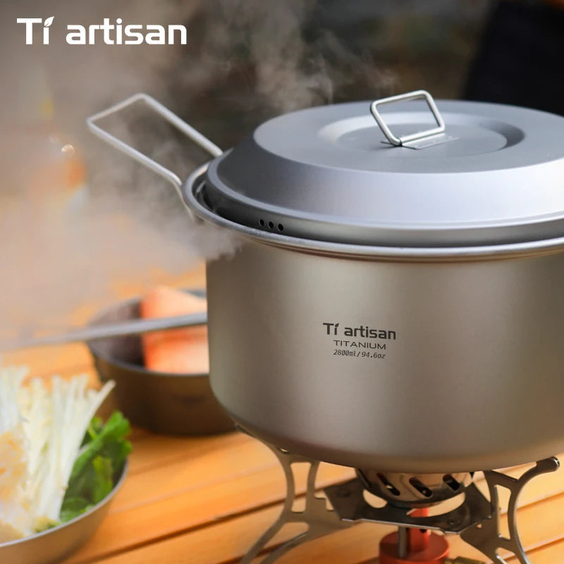Titanium cookware set on a stove with steam rising, featuring the Tiartisan brand.